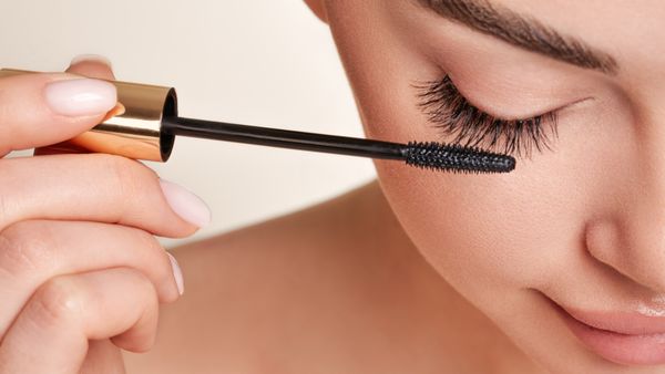 Frau hält Mascara in Nahaufnahme an ihre Wimpern - Foto: istock/ heckmannoleg 